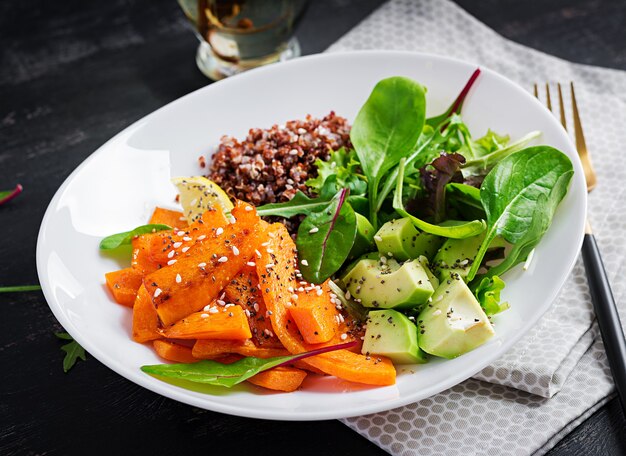 Repas végétaliens, déjeuner. Buddha bowl avec quinoa, tranches de citrouille frites, avocat et herbes vertes