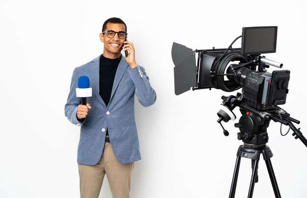 Reporter African American Man Holding A Microphone Et Rapport De Nouvelles Sur Fond Blanc Isolé En Gardant Une Conversation Avec Le Téléphone Mobile Avec Quelqu'un