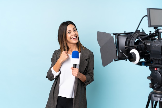 Reporter femme tenant un microphone et rapportant des nouvelles célébrant une victoire