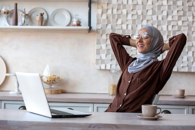 Repos après l'apprentissage à distance, une jeune étudiante musulmane en hijab est assise à la maison à la table devant