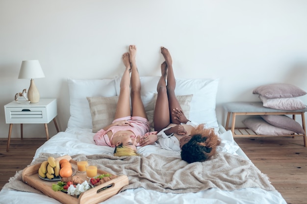 Repos, détente. Jeunes copines élancées adultes en lingerie allongé sur le lit avec les jambes dans la chambre à la maison