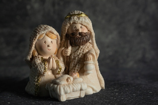 Représentation d'une crèche de Noël avec les petites figures de l'enfant Jésus, Marie et Joseph sur fond de roche.