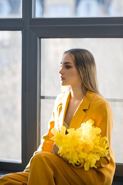 Photo représente une personne qui sent une fleur jaune à l'extérieur la personne est une femme