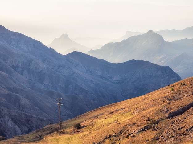 Réseau de fils et de poteaux télégraphiques sur les collines brumeuses d'automne. Paysage brumeux de montagne atmosphérique au Daghestan.