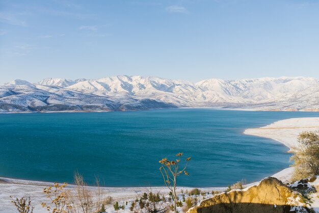 Réservoir de Charvak en Ouzbékistan en hiver avec de l'eau bleue, entouré par le système de montagnes du Tien Shan