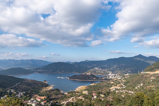 Le réservoir sous le ciel bleu et les nuages blancs est entouré de montagnes et de forêts