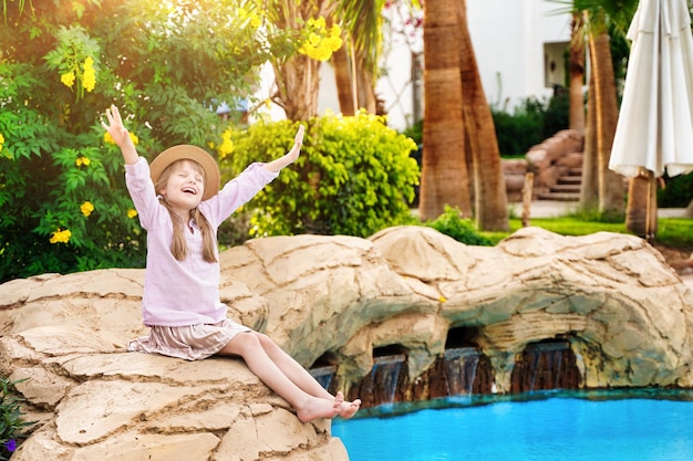 Resort hôtel enfant fille assise au bord de la piscine, bronzer heureux. Repos et relaxation. Photo de haute qualité