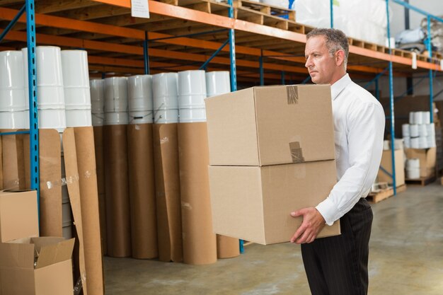 Responsable d&#39;entrepôt transportant des boîtes en carton