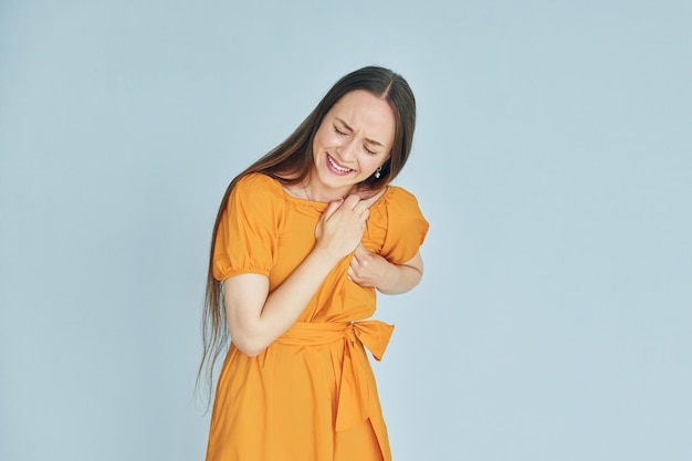 Ressent la douleur Jeune femme en vêtements décontractés debout à l'intérieur dans le studio