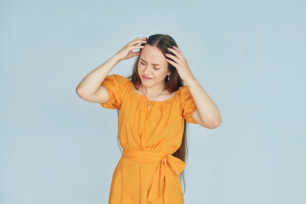 Ressent la douleur Jeune femme en vêtements décontractés debout à l'intérieur dans le studio