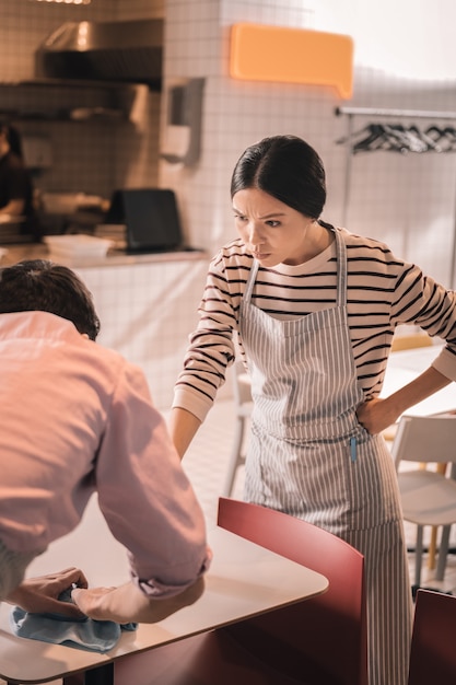 Ressentez de la colère. Propriétaire de restaurant aux cheveux noirs ressentant de la colère après avoir vérifié le travail du serveur