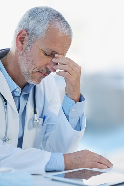 Ressentir la tension Photo recadrée d'un médecin mature se sentant stressé au travail