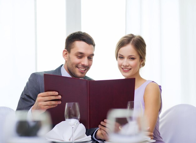 restaurant, couple et concept de vacances - couple souriant avec menu au restaurant