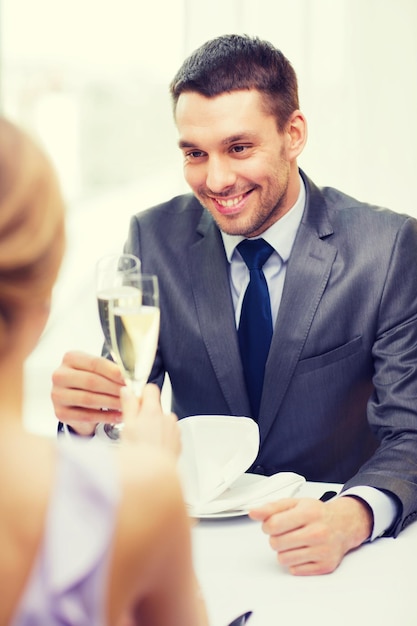 restaurant, couple et concept de vacances - homme souriant avec une coupe de champagne regardant sa femme ou sa petite amie au restaurant