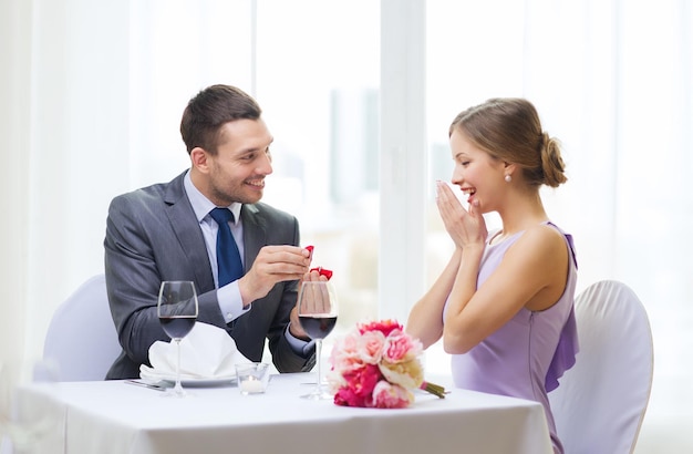 restaurant, couple et concept de vacances - homme souriant proposant à sa petite amie au restaurant