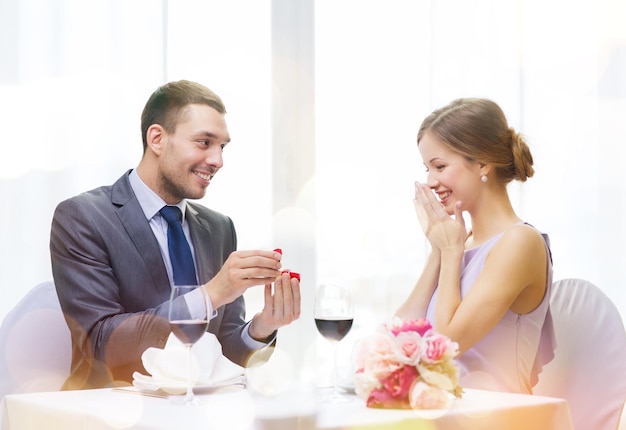 restaurant, couple et concept de vacances - homme souriant proposant à sa petite amie au restaurant