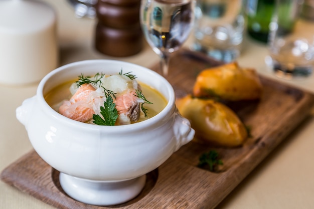 Restaurant servant un plat - soupe de saumon sur planche de bois avec tarte, boisson sur table