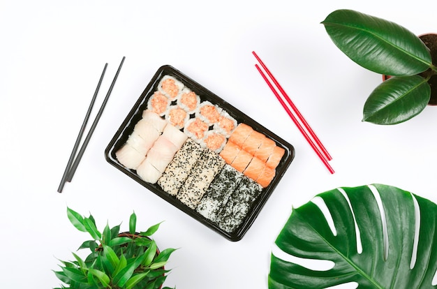 Photo restauration de cuisine japonaise. sushi avec des baguettes, à surface blanche à emporter