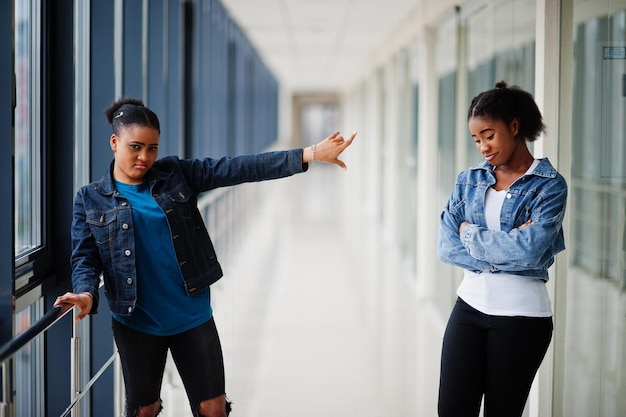 Reste loin de moi. Deux amies africaines en veste de jeans ont posé ensemble à l'intérieur.