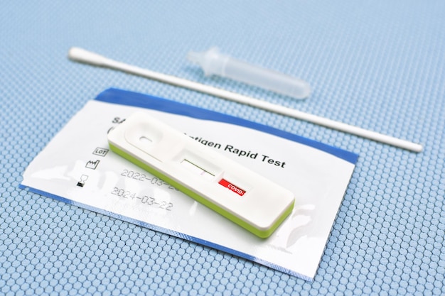 Photo résultat du test négatif covid19 du kit de test d'antigène atk sur fond de couleur bleu clair avec un écouvillon de coton de tube d'extraction de cassette