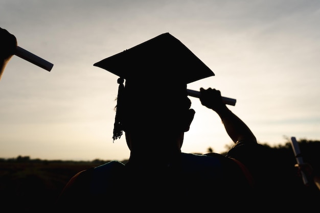 Photo résumé gros plan groupe de vue arrière des diplômés universitaires au coucher du soleil silhouette