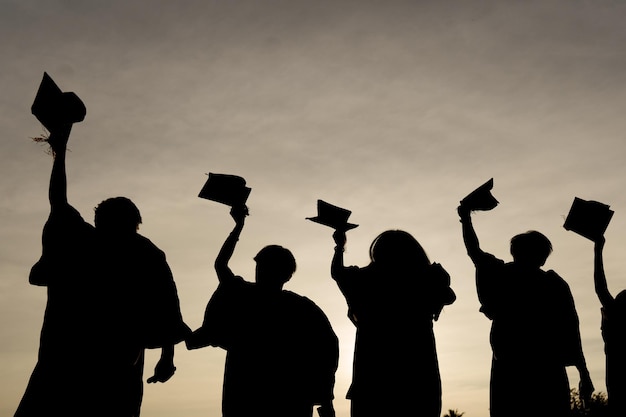 Photo résumé gros plan groupe de vue arrière des diplômés universitaires au coucher du soleil silhouette