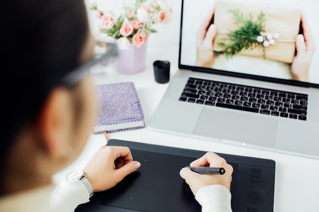 retouche femme sur ordinateur portable à l'aide d'une tablette numérique et d'un stylet