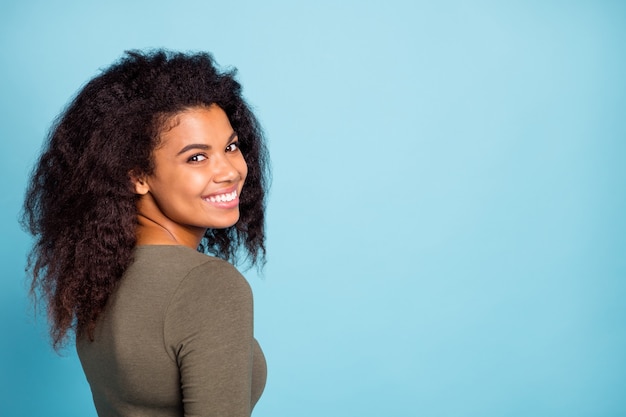 Retour arrière vue latérale photo de charmante belle fille afro-américaine tourner le stand copyspace regarder écouter se sentir positif joyeux plaisir émotion porter élégant cavalier isolé sur mur de couleur bleu