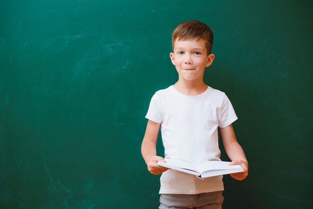 Retour au concept de l'école. Écolier en classe. Enfant heureux contre le tableau vert. Enfant intelligent en classe. Idée et concept d'éducation