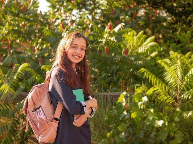 Retour au concept de l'école Fille adolescente écolière souriante avec bloc-notes et sac à dos.