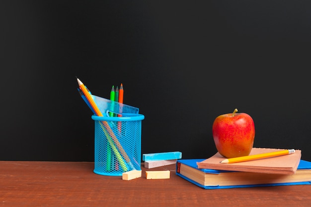 Retour au concept d'école. Tableau noir avec des livres et pomme sur un bureau en bois