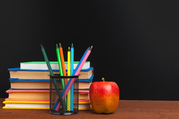 Retour au concept de l'école. Tableau noir avec livres et pomme sur un bureau en bois