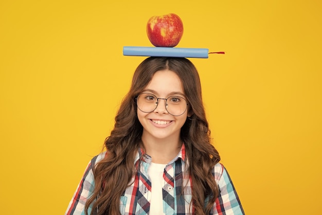 Retour à l'école Adolescent écolière avec pomme sur la tête prête à apprendre les écoliers sur fond jaune isolé