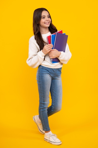 Retour à l'école Écolière adolescente avec livre prêt à apprendre Écolières sur fond de studio jaune isolé Visage heureux émotions positives et souriantes d'une adolescente