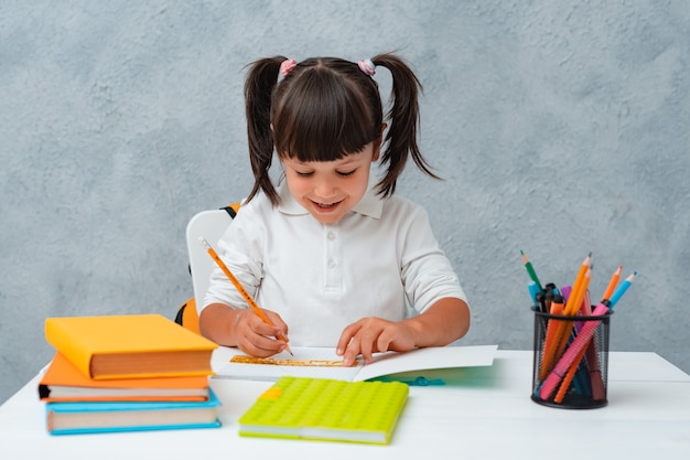 Retour à l'école. Écolière enfant mignon assis à un bureau dans une pièce.