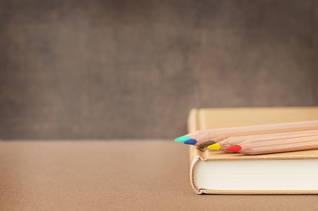 Retour à l'école et concept d'éducation Crayons en bois colorés sur un livre près du tableau noir et place pour le texte