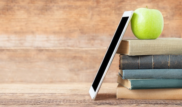 Retour à l'école et concept d'éducation Une pile de livres tablette et pomme verte sur le fond en bois