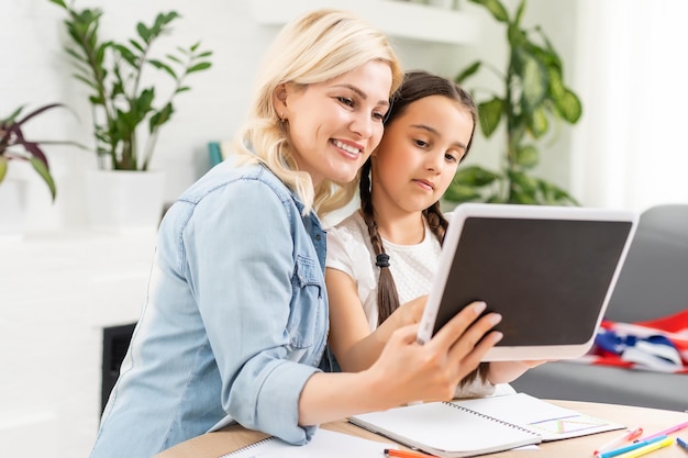 Retour à l'école. Un enfant et un adulte heureux sont assis au bureau. Fille faisant ses devoirs ou éducation en ligne.