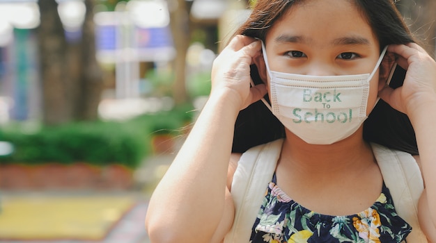 Retour à L'école. Enfant Asiatique Fille Portant Un Masque Facial Avec Sac à Dos Aller à L'école. Pandémie De Coronavirus.nouveau Mode De Vie Normal.concept D'éducation.