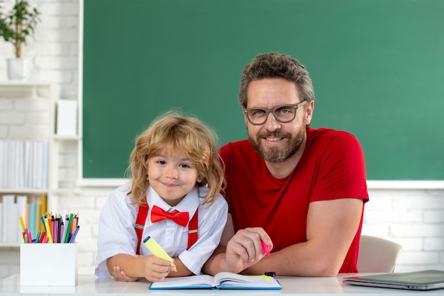Retour à l'école enfant garçon apprenant avec le professeur drôle petit garçon étudie avec le père en classe sur blackboa