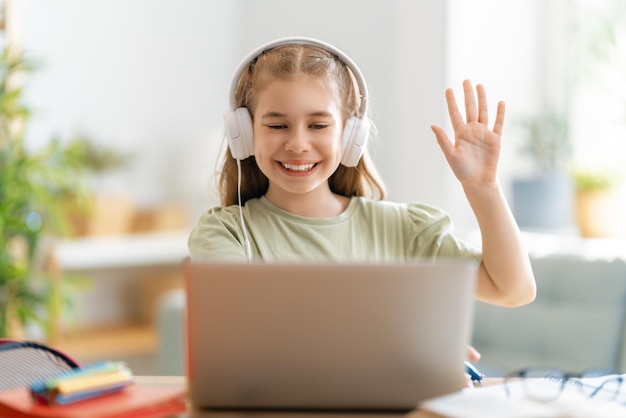 Retour à l'école. Un enfant heureux est assis au bureau. Fille faisant ses devoirs ou éducation en ligne.