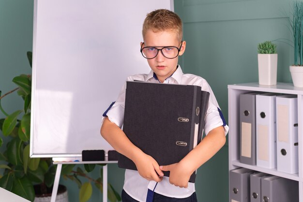 Retour à l'école, un enfant travailleur est assis à une table à l'intérieur, un étudiant lit un livre