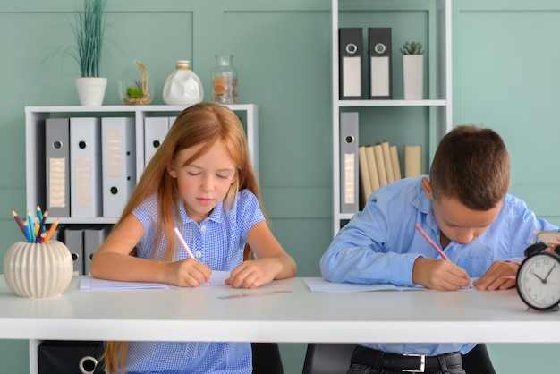 Retour à l'école des enfants qui travaillent dur, assis à une table à l'intérieur, un étudiant lit un livre