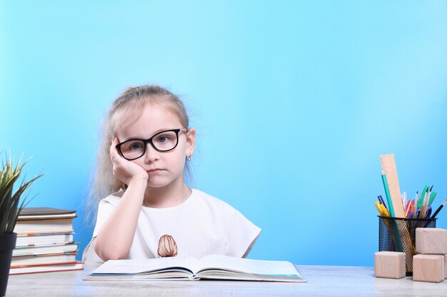 Retour à l'école. Heureux enfant industrieux mignon est assis à un bureau à l'intérieur. L'enfant apprend en classe.