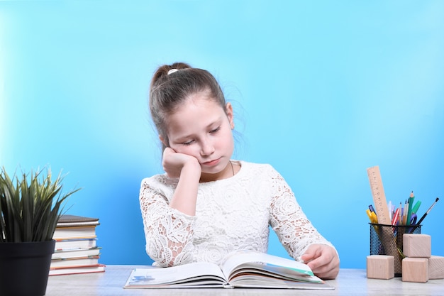 Retour à l'école. Heureux enfant industrieux mignon est assis à un bureau à l'intérieur