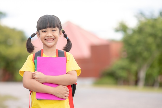 Retour à l'école. jolies filles asiatiques avec sac d'école tenant un livre ensemble à l'école