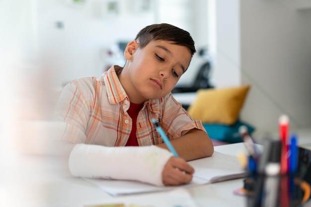 Retour à l'école penser enfant garçon dessin écrit dans un cahier assis au bureau et faire ses devoirs hig