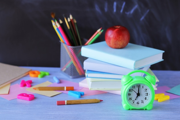 Retour à l'école, pile de livres, horloge, papeterie sur la table