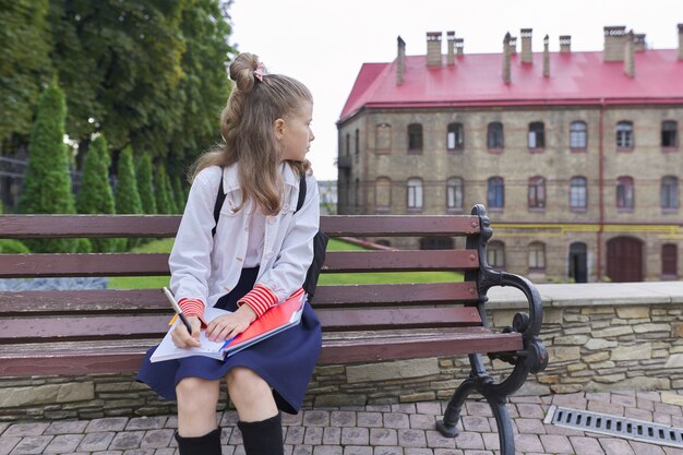 Retour à l'école. Portrait en plein air de la belle fille blonde avec sac à dos écrit dans le cahier