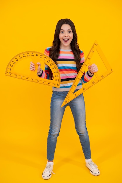 Retour à l'école School girl tenir la règle de mesure isolé sur fond jaune Heureux adolescent émotions positives et souriantes d'écolière adolescente